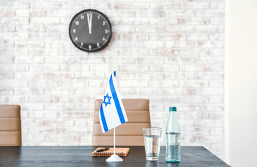 Bottle and glass with water and flag of Israel on table in embassy office
