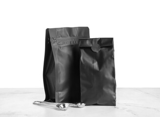 Bags with coffee and spoons on table against white background