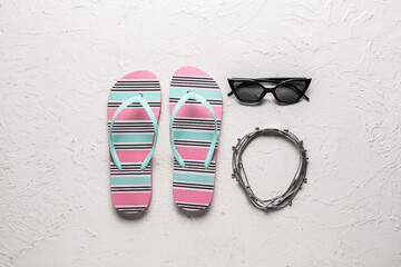 Stylish flip-flops and sunglasses on white  background