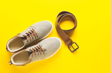 Stylish shoes and leather belt on color background
