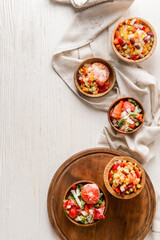 Frozen vegetables in bowls on light background