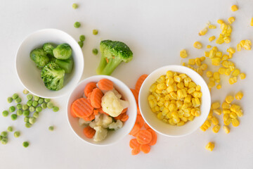 Frozen vegetables in bowls on white background