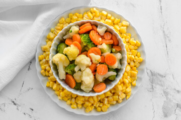 Frozen vegetables in bowl on light background