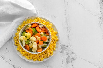 Frozen vegetables in bowl on light background