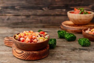 Frozen vegetables in bowls on wooden background