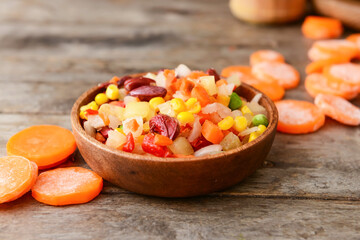 Fototapeta na wymiar Frozen vegetables in bowl on wooden background