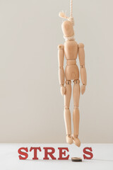 Hanged wooden human figure and word STRESS on light background