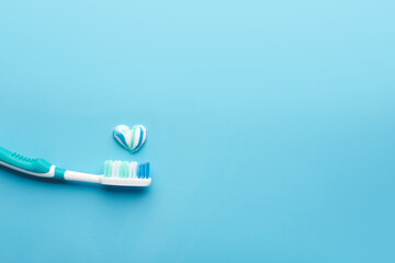 Toothbrush and heart made of paste on color background