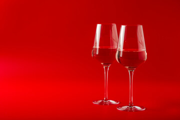 Romantic Celebration Of Valentine's Day. Two full glasses of wine on red background. Beautiful background, concept for February 14, love symbol or romantic date. Copy space