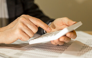 Calculating budget at office desk, close up of male hands