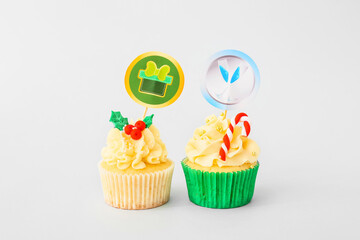 Tasty Christmas cupcakes on light background
