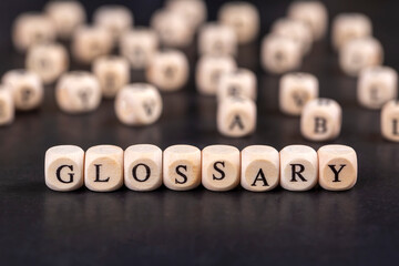 Glossary - word from wooden blocks with letters, alphabetical list with words meanings dictionary...