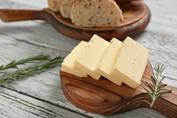 Chopping board with fresh butter and tasty bread on wooden table