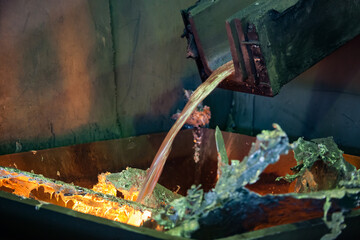 Liquid melting aluminium flow out of the furnace. Close-up.