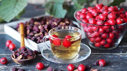 Bright berries of fresh hawthorn with dried berries and tea on a wooden background. Alternative folk medicine using hawthorn.
