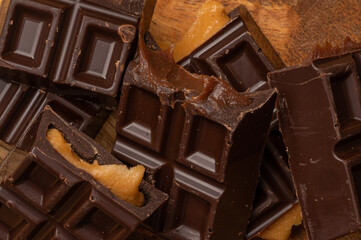 Pieces of chocolate bar filled with chocolate and vanilla cream on wooden plate