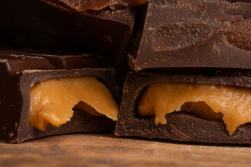 Pieces of chocolate bar filled with chocolate and vanilla cream on wooden plate