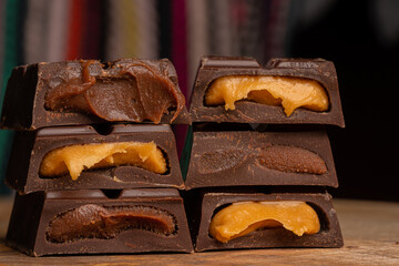 Pieces of chocolate bar filled with chocolate and vanilla cream on wooden plate