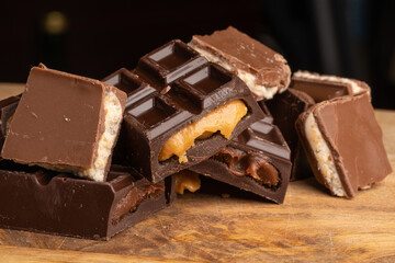 Pieces of chocolate bar filled with chocolate and vanilla cream on wooden plate