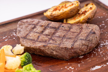 Meat grilled ribai with vegetables. Ribai steak on wooden board. Close up