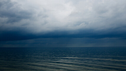Moody dramatic dark contrasting clouds over calm sea. Storm approaching. 