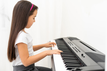 Cute little girl has training course with piano