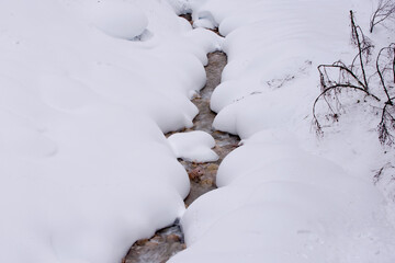 uno splendido paesaggio montano innevato, un fiume scorre i mezzo a montagne di neve, la magia dell'inverno in montagna © giovanni