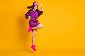 Full size portrait of attractive lady jumping won fist hooray wear plaid cap isolated on yellow color background