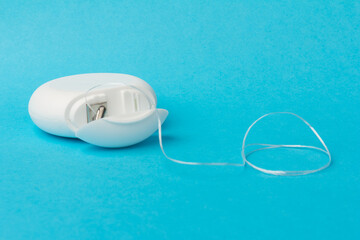 Dental floss container on blue background. Daily oral hygiene, teeth care and health. Cleaning products for your mouth, copy space. Dental care concept.