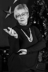 Studio portrait of blonde adult woman with short hair in purple woolen dress near new year tree