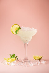 Cocktail margarita garnished with lime and mint on pink background