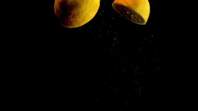 lemon halves falling, drop into water with air bubbles and a smooth black background. perfect for advertising or commercial videos for lemonade, juice and cocktails. Also perfect for  baar and drinks