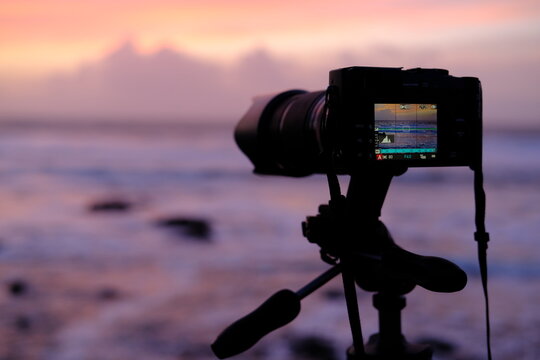 A camera taking picture of a sunset on the seaside.