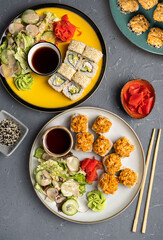 Japanese sushi food. Round light plate with rolls, ginger and salad on a gray concrete background. Top view