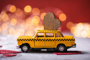 Red heart on toy yellow  taxi car on red background. Travel love concept with copy space.