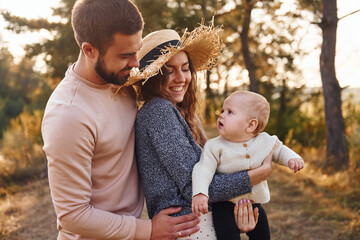 Obraz premium Happy family of mother, family and little baby rests outdoors. Beautiful sunny autumn nature