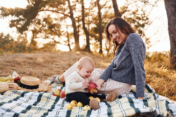 Young mother with her little baby rests outdoors at autumn season