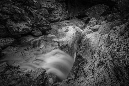 Small waterfalls of transparent water in a rocky gorge, Dolomiti Bellunesi National Park, Dolomites, Italy. Long exposure and black and white photo