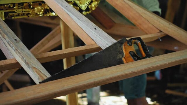 Hand saw for wood processing lying on a wooden structure part of which is decorated with gold paint
