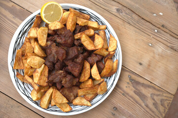 grilled pork with french fries and salad on a wooden table