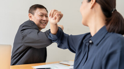 Two Asian colleagues avoid a handshake when meeting in the office greeting with bumping elbows during coronavirus COVID-19 epidemic in office, Social distancing concept.