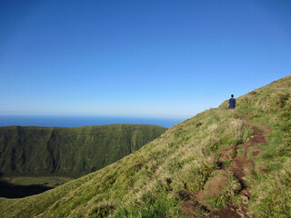 woman hiking alone on volcanic path trail around Caldeira, Faial, Azores.