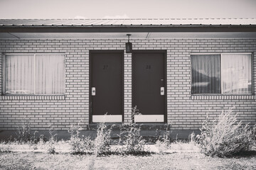 Old abandoned seedy motel, with overgrown weeds in the parking lot