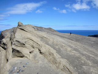 Fototapeta na wymiar Woman hiking to one of the peaks at Capelinhos volcano, Faial, Azores.