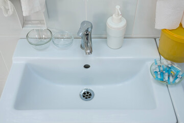 Fototapeta premium White sink in hospital room with liquid soap and medical things. Equipment for maintaining cleanliness and sterility in the hospital.