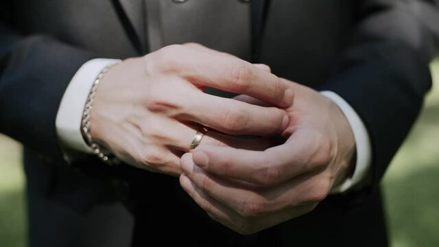 Close-up of a caucasian man in a suit twirls a gold wedding ring on his finger