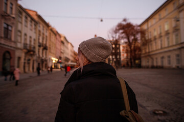 young woman walks in the evening old town