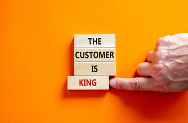 Customer is king symbol. Wooden blocks with words 'The customer is king'. Male hand. Beautiful orange background. Business and customer is king concept. Copy space.