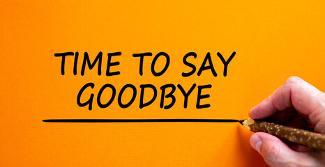 Time to say goodbye symbol. Hand writing 'Time to say goodbye', isolated on beautiful orange...