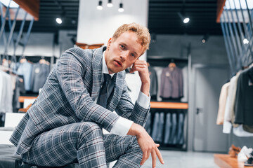 Young guy in modern store with new clothes. Elegant expensive wear for men